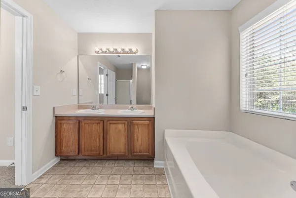a spacious bathroom with a bathtub a sink a mirror and a window