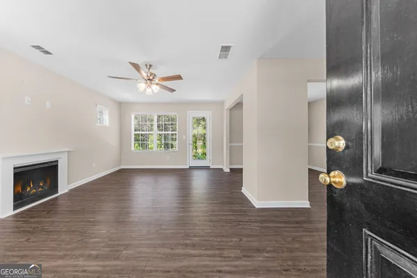 an empty room with wooden floor a ceiling fan and windows