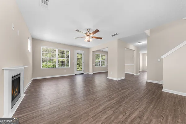 an empty room with wooden floor and a ceiling fan
