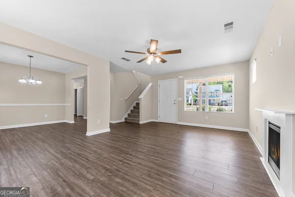 an empty room with wooden floor a ceiling fan and windows