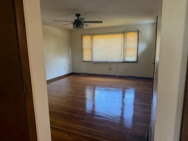 a view of an empty room with wooden floor and a window