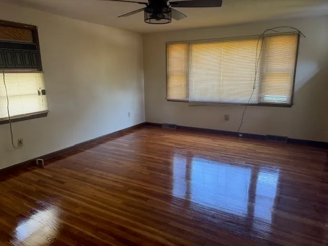 a view of an empty room with wooden floor and a window