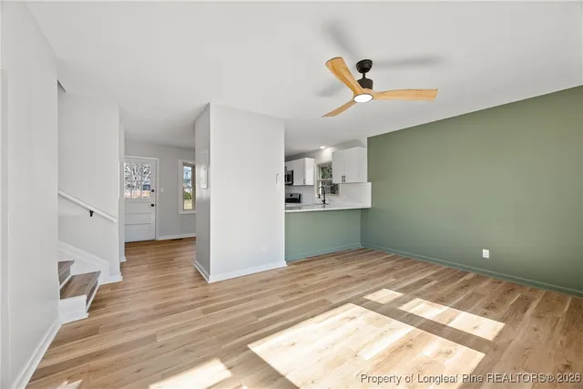 a view of kitchen and empty room with wooden floor