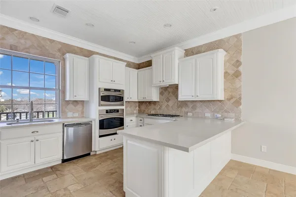 a kitchen with white cabinets and appliances