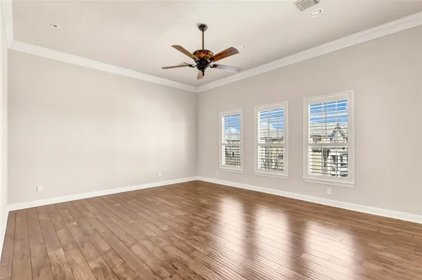an empty room with wooden floor fan and windows