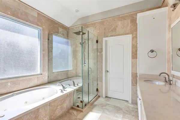 a bathroom with a tub shower sink and mirror