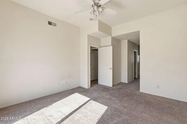 an empty room with a chandelier fan and entryway