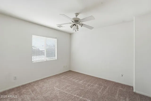 an empty room with a window and a fan