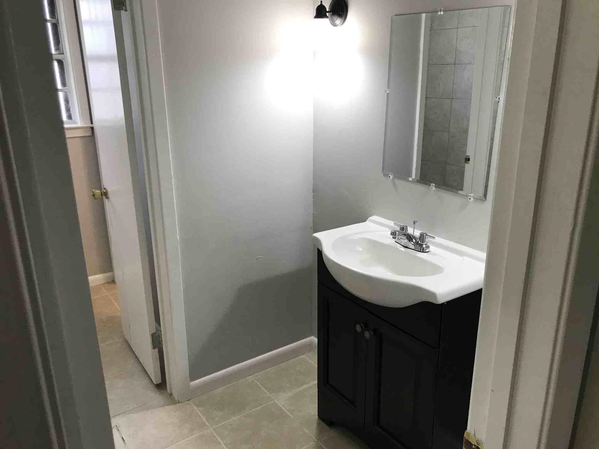 4502 Cottonwood Road Memphis, TN 38118 - Photo 12 of 16 Bathroom featuring a dark wood-finish vanity with a white integrated sink, chrome faucet, and rectangular mirror