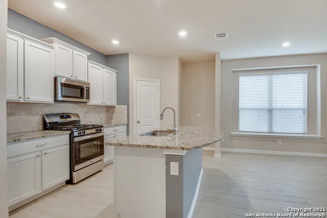 a kitchen with stainless steel appliances granite countertop a stove a sink and a microwave