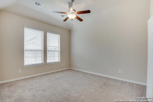 an empty room with chandelier fan and windows