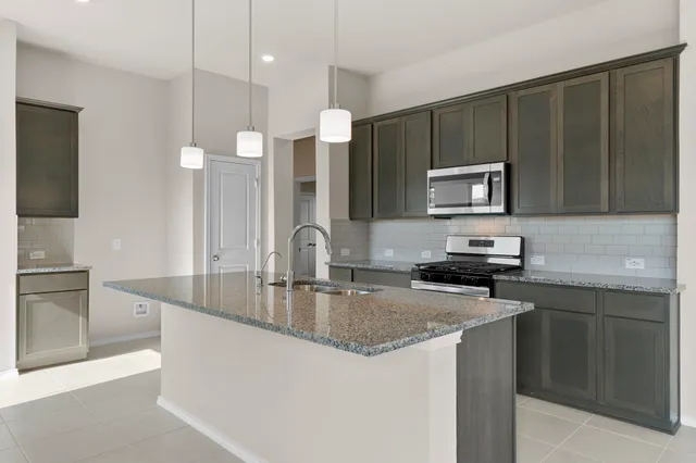 a kitchen with kitchen island granite countertop a sink stove and refrigerator