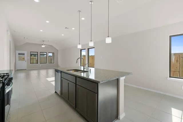 a kitchen with stainless steel appliances granite countertop a sink a stove and a wooden floor