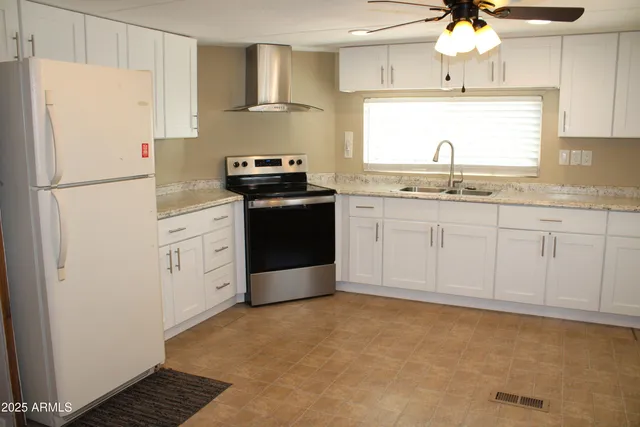 a kitchen with granite countertop a sink cabinets stainless steel appliances and a refrigerator