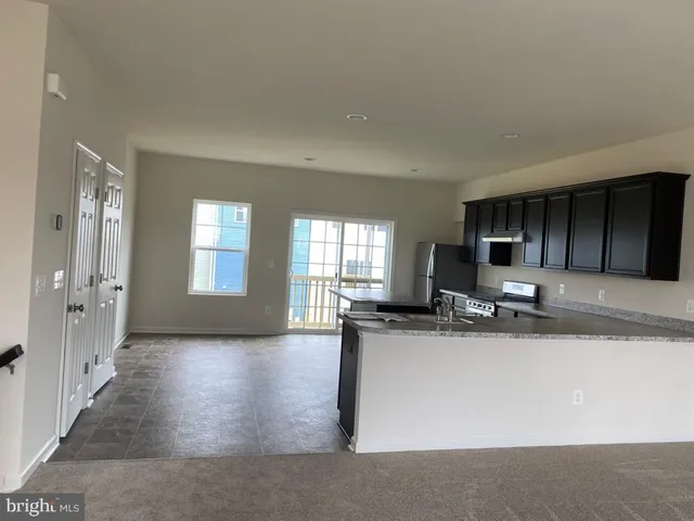 a view of a kitchen with kitchen island a sink wooden floor and living room view