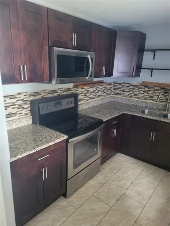 a kitchen with granite countertop a refrigerator a stove and cabinets