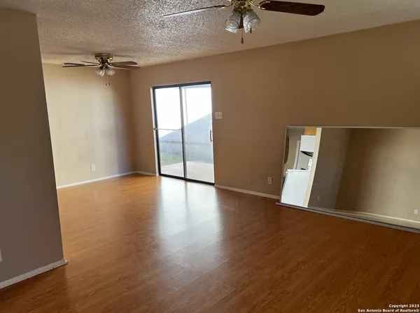 an empty room with wooden floor fan and windows