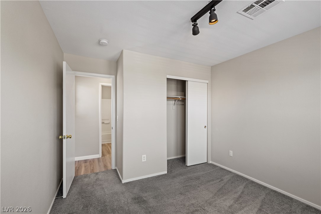 8777 Roping Rodeo Avenue, Unit 101 Las Vegas, NV 89178 - Photo 20 of 25 A well-lit bedroom offers plush carpeting and a convenient closet, leading to an adjoining bath with wood flooring.