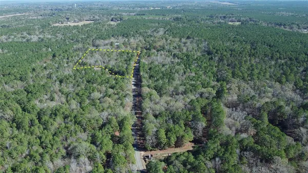 an aerial view of residential house with outdoor space and trees all around