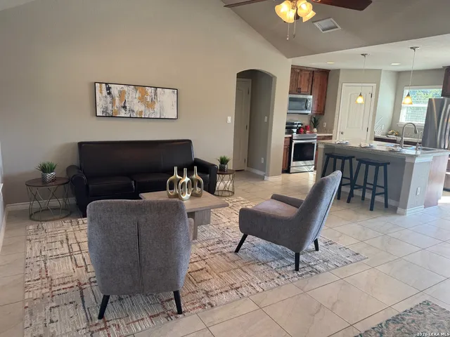 a living room with furniture and a dining table with kitchen view