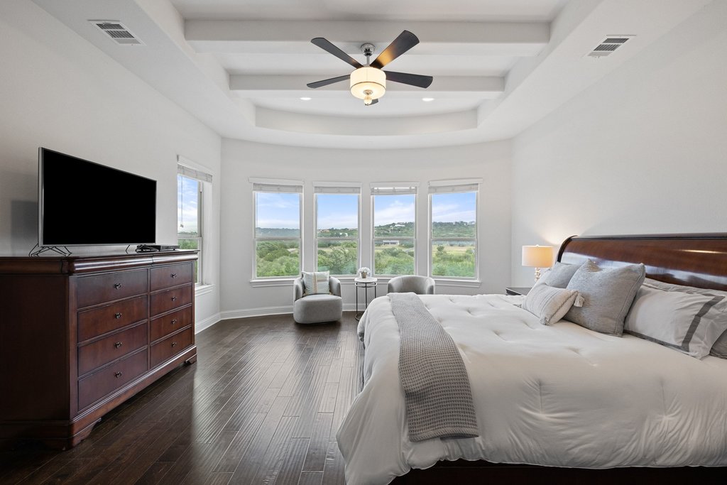 215 Lodestone Lane Austin, TX 78738 - Photo 19 of 40 A spacious primary bedroom features rich hardwood flooring and a picturesque green landscape view.