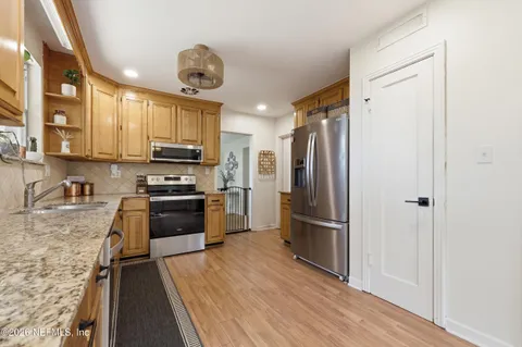 a kitchen with stainless steel appliances granite countertop a refrigerator a stove and a sink with wooden floor