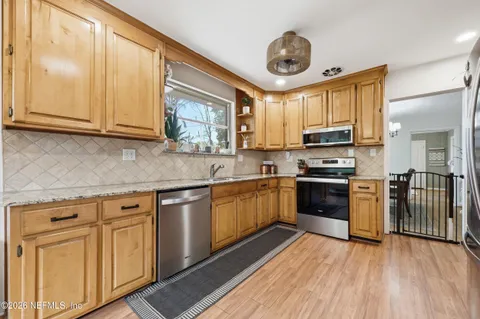 a kitchen with granite countertop a sink cabinets stainless steel appliances and a window
