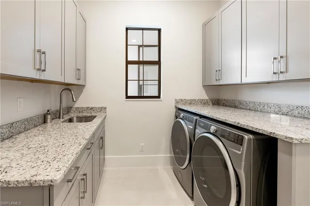a utility room with granite countertop a sink a washer and dryer