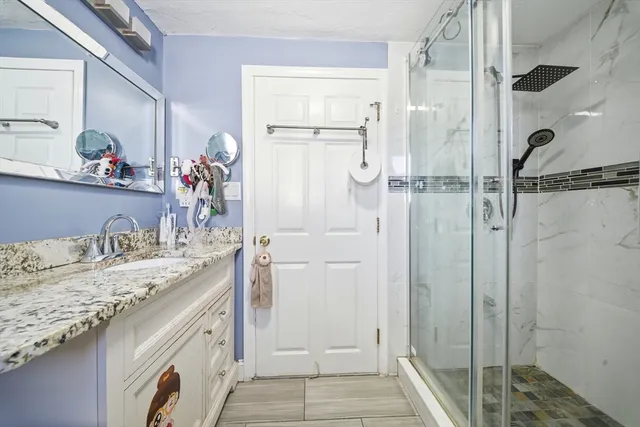 a bathroom with a granite countertop sink mirror and shower