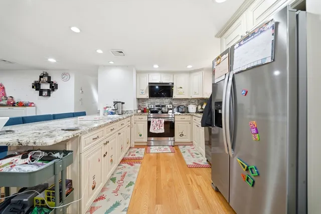 a kitchen with stainless steel appliances granite countertop a refrigerator and a stove top oven