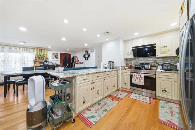 a kitchen with granite countertop a stove top oven a sink dishwasher and a dining table with wooden floor