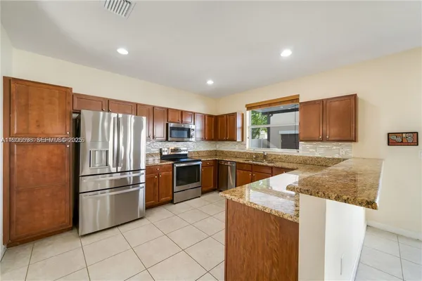 a kitchen with stainless steel appliances granite countertop a refrigerator sink and stove