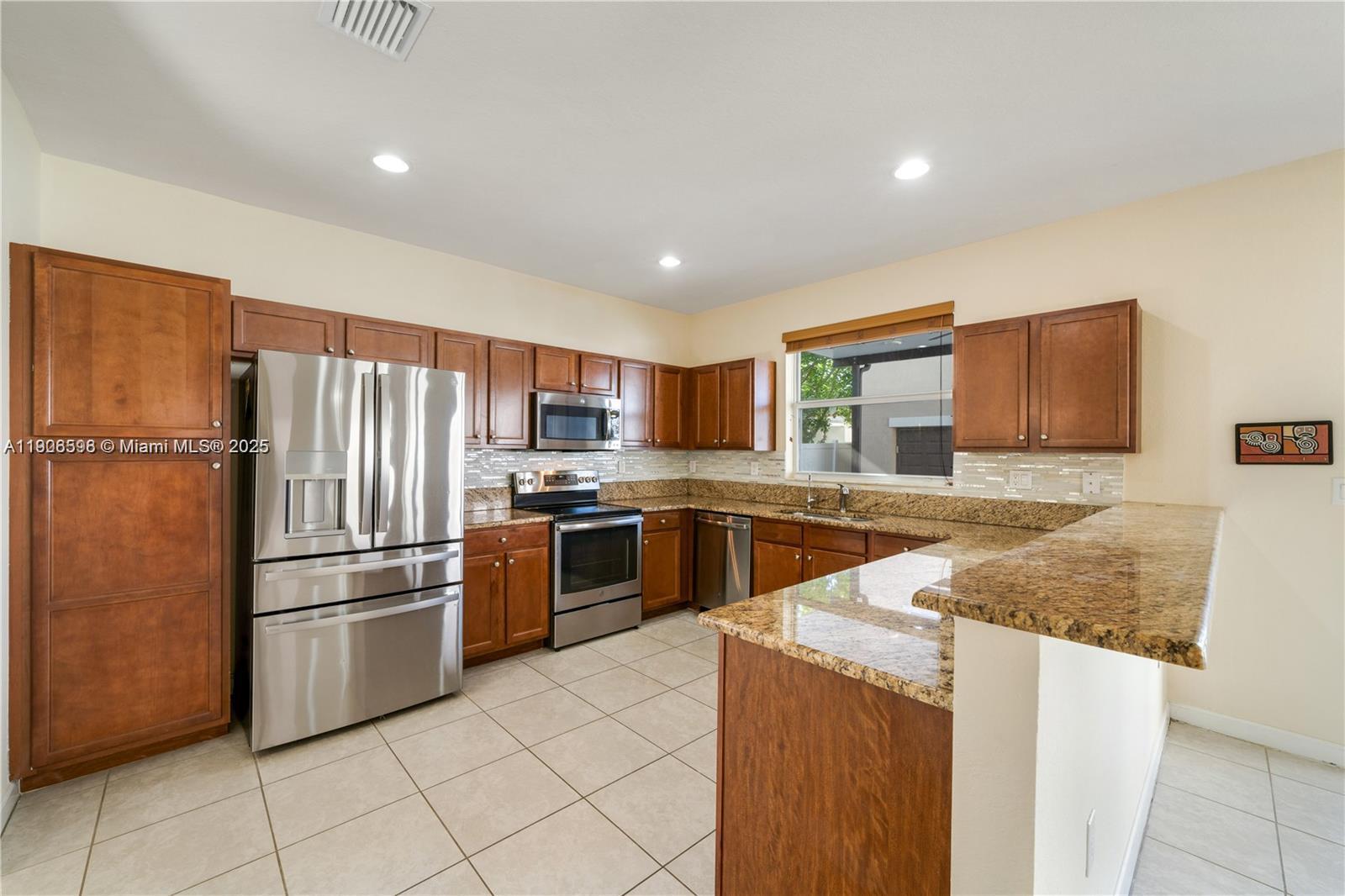 16946 Southwest 90th Terrace Circle Miami, FL 33196 - Photo 3 of 36 a kitchen with stainless steel appliances granite countertop a refrigerator sink and stove