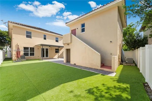 a view of a white house in front of a big yard