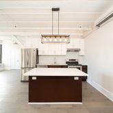 a kitchen with a stove a window and chairs