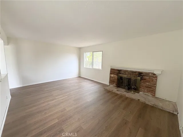 an empty room with wooden floor and fireplace