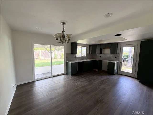 an empty room with wooden floor and a kitchen