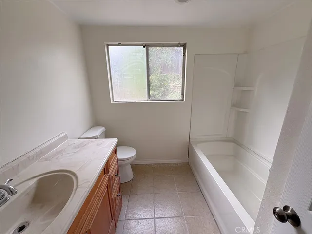 a bathroom with a granite countertop sink a toilet and bathtub
