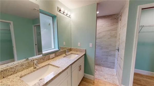 a bathroom with a granite countertop double vanity sink and a mirror