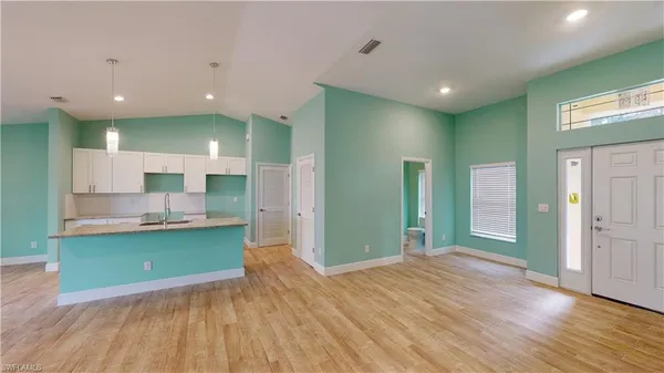 a view of kitchen with kitchen island a sink wooden floor and a living room