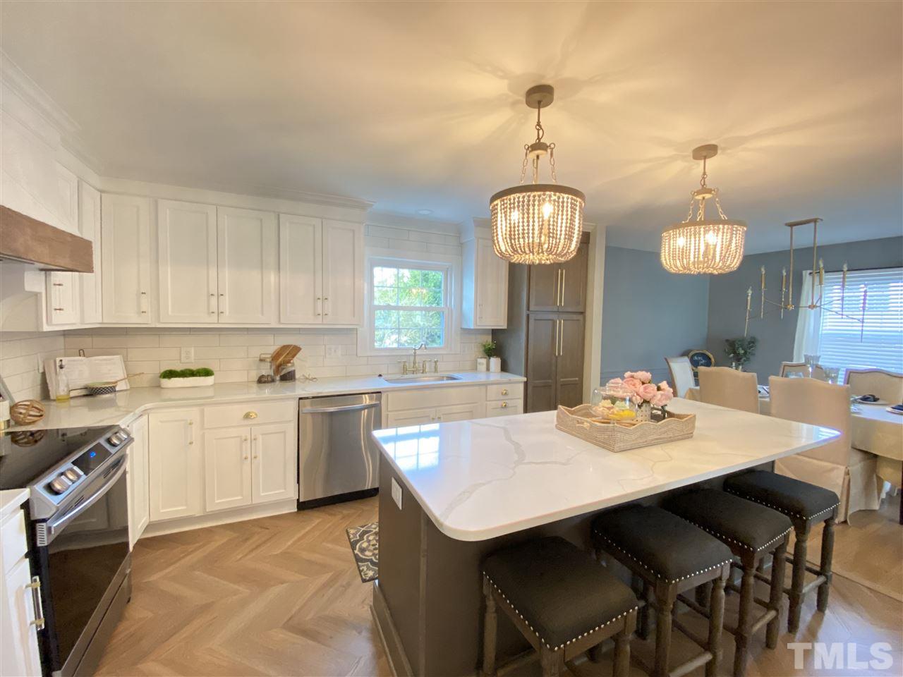 917 Deerfield Road Raleigh, NC 27609 - Photo 5 of 20 a kitchen with a dining table wooden floor and stainless steel appliances