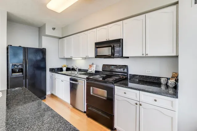 a kitchen with stainless steel appliances granite countertop white cabinets a stove a microwave a sink and refrigerator