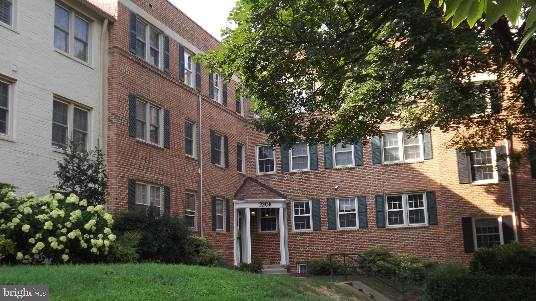 a front view of a house with a garden and trees