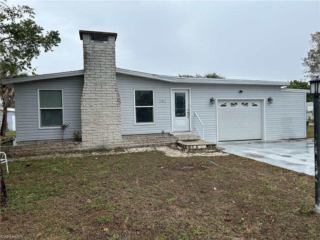 181 Pine Key Lane, Unit 29 Naples, FL 34114 - Photo 2 of 20 View of front of property featuring an attached garage, driveway, and a chimney