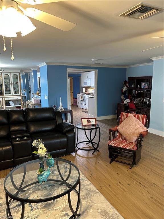 181 Pine Key Lane, Unit 29 Naples, FL 34114 - Photo 7 of 20 Living room with a ceiling fan, light wood-style flooring, and crown molding
