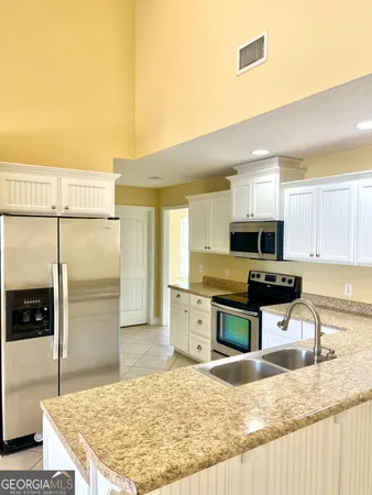 a kitchen with stainless steel appliances granite countertop a sink refrigerator and cabinets
