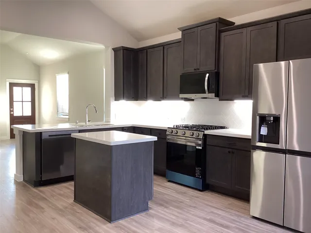 a kitchen with granite countertop a refrigerator and a stove top oven