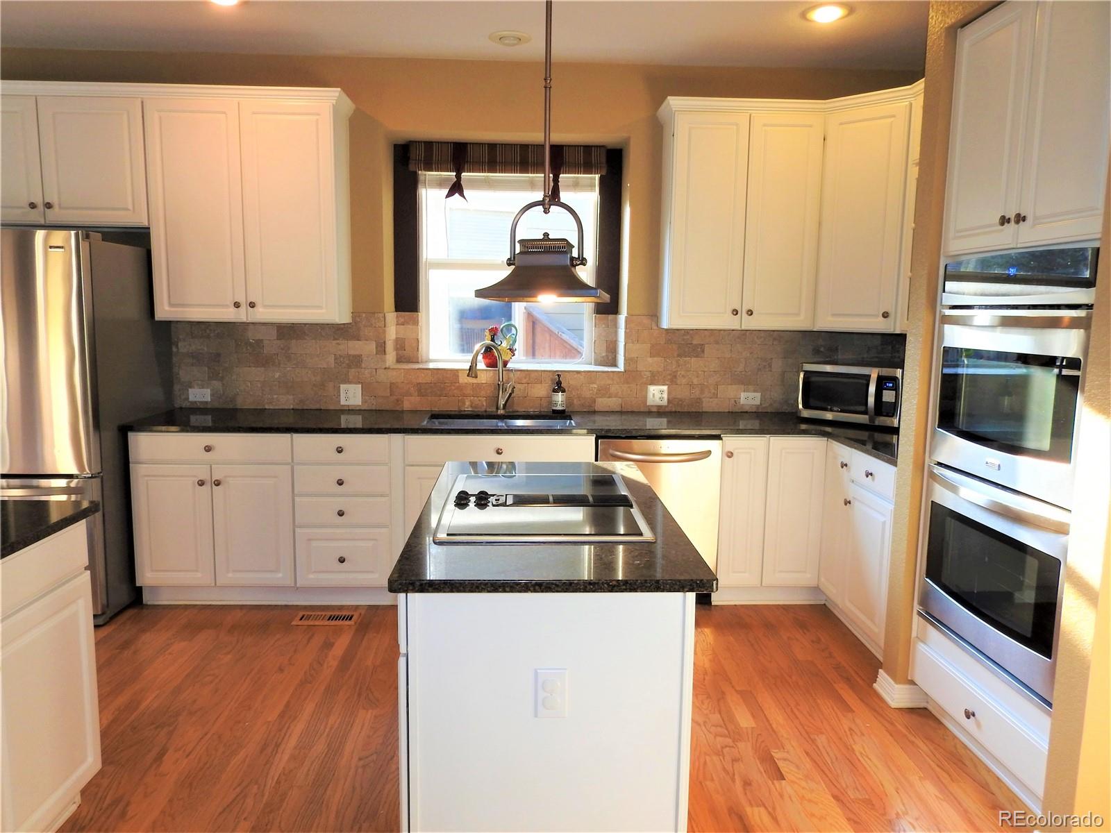 455 West Angus Way Highlands Ranch, CO 80129 - Photo 11 of 27 a kitchen with stainless steel appliances granite countertop a stove a sink and white cabinets