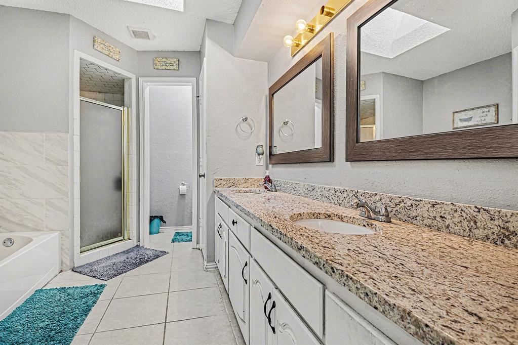 2433 Hallmark Street Grand Prairie, TX 75052 - Photo 11 of 15 a spacious bathroom with a granite countertop sink a mirror and a bathtub