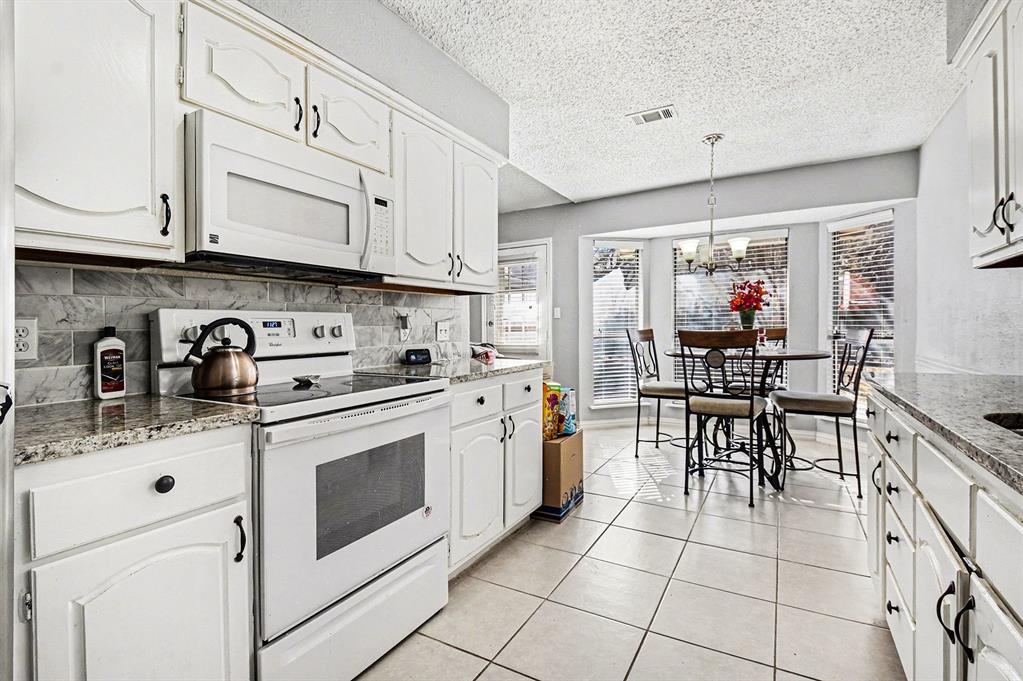2433 Hallmark Street Grand Prairie, TX 75052 - Photo 9 of 15 a kitchen with stainless steel appliances granite countertop a sink and cabinets